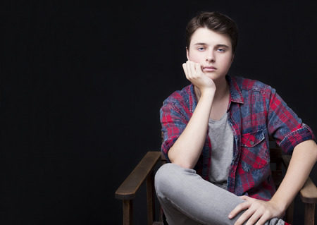 Guy sitting on a chair against black studio backgroundの写真素材