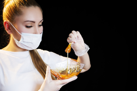 Woman with sugar hair removing paste on black backgroundの写真素材