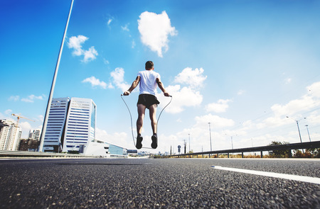 Portrait of muscular young man exercising with jumping rope.の写真素材