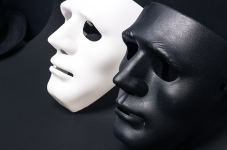 White and dark human masks isolated on black backgroundの写真素材