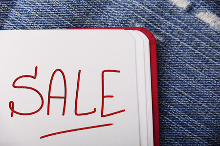 SALE word written in the notebook on a jeans backgroundの写真素材