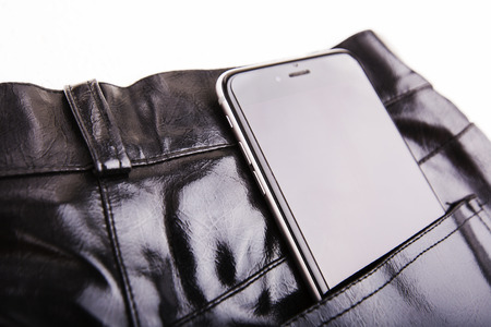 A close-up of a piece of black leather cloth on white background with phoneの写真素材