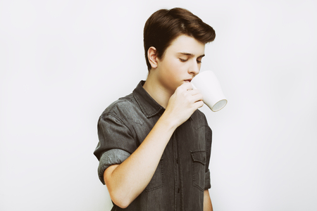 Coffee break. Confident young handsome man in jeans shirt holding cup with hot drinkの写真素材