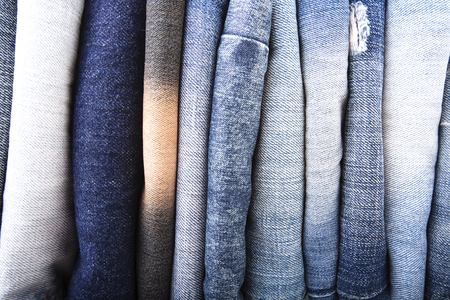 Stack of folded clothes, blue jeans pants, dark blue denim trousers isolated on white backgroundの写真素材