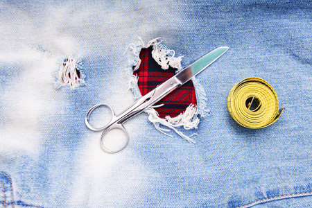Tailoring and design concept. Metal scissors ruler and yellow measure tape in denim pants pockets.