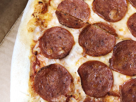 Close-up thinly sliced pepperoni on fresh Italian classic original Pizza. Pepperoni is a popular pizza topping in American-style pizzerias.の写真素材