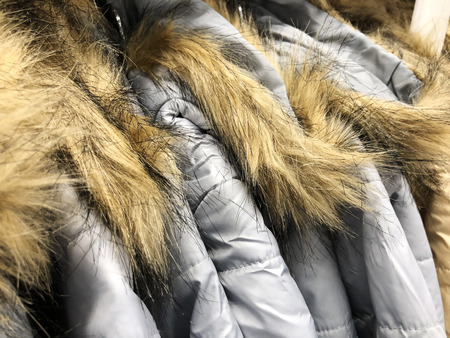 Men's and women's jackets and down jackets on the counter in the storeの写真素材