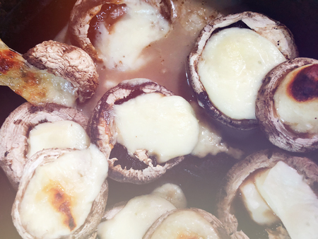 Fried mushrooms in a creamy sauce and cheese cooked in a frying pan.の写真素材