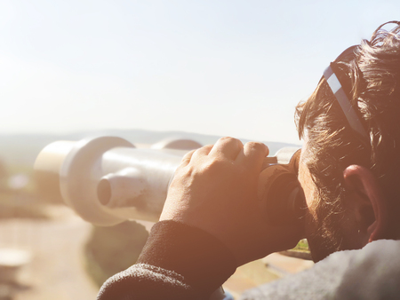 Tourist looks in the binoculars tower viewer at the city view. Tower viewer is a popular device for...