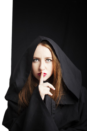 Beautiful redhead young pregnant woman in a black cloak with a hoodの写真素材