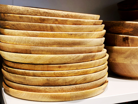 Many plates on store shelves. Wooden plates. The background of the platesの写真素材