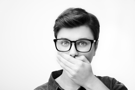 Young man feeling confused with eyeglasses isolated on whiteの写真素材