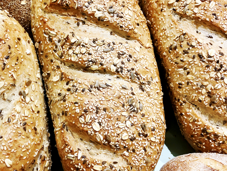 A lot of fresh bread with buns on the table. Bread business. Fresh buns from cereals with seeds from...