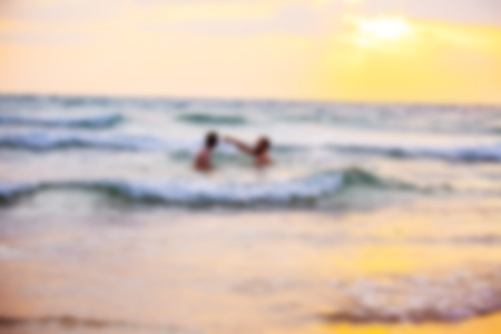 Abstract blurred background. Beautiful sunset with sea and beach. Blurred people swimming at the sea.の写真素材