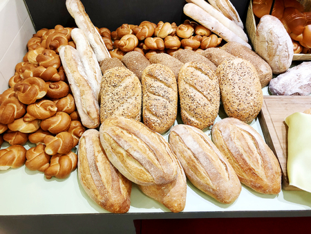 A lot of fresh bread with buns on the table. Bread business. Fresh buns from cereals with seeds from...