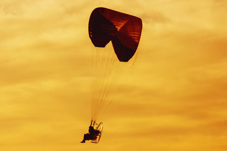 A man is flying on a paraglider over the sea against the backdrop of a beautiful sunset in Israel