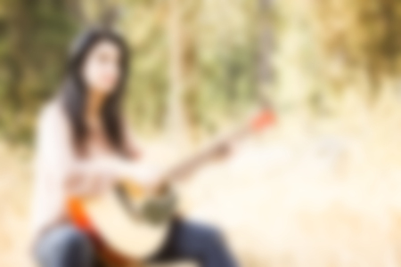 Abstract blurred background. Young female musician playing musical instrument at natureの写真素材