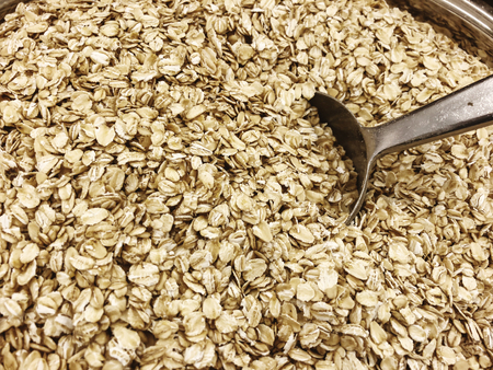 Top view or oat flakes with metallic scoop close up.