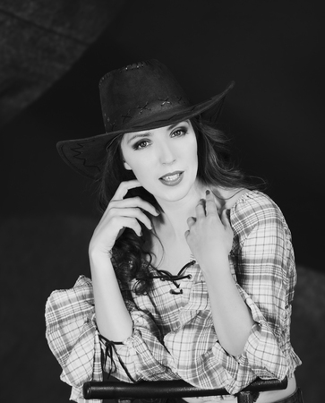Beautiful brunette cowgirl in cowboy hat on dark backgroundの写真素材