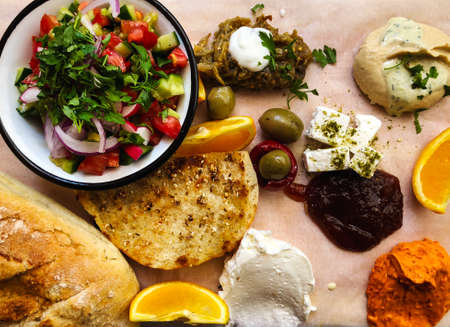 Delicious breakfast: tomatoes and cucumbers, bread, cheese, olives and orange.