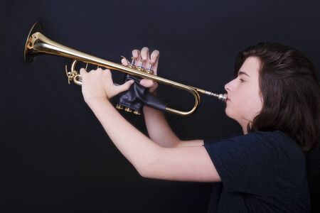 Portrait of a teenager playing trumpet in studioの写真素材