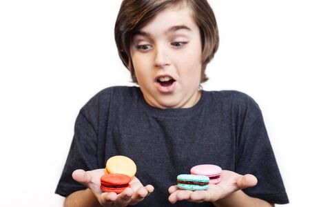 Surprised handsome boy looks on macaron on white backgroundの写真素材