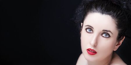 Young attractive woman with long black hair on dark background.の写真素材