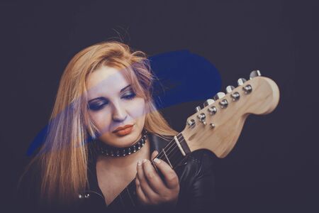 Beautiful blonde girl in rock style on a black background.の写真素材