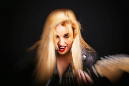 Beautiful blonde girl in rock style on a black background. Blur motion effect