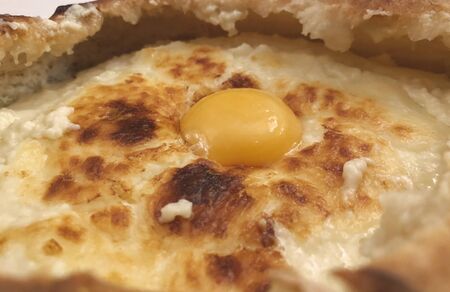 Georgian national cuisine - freshly baked adjarian khachapuri on the plate at the restaurant.