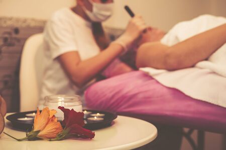 Young woman receiving facial epilation close up. Cosmetologist removes hair on face. Beauty salon, mustache depilation.の写真素材