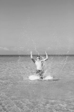young muscular man posing and splashing around in the sea.の写真素材