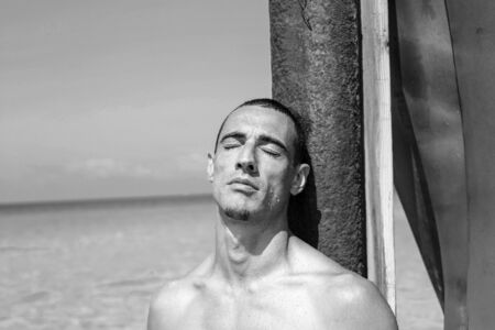 young muscular man resting and posing on the beach.