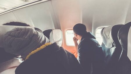 Passenger traveler looking at window in airplane, travel by flight, man tourist sitting in air plane. Travel conceptの写真素材