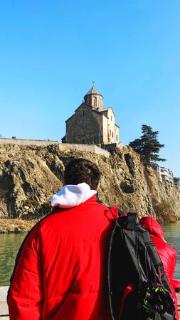 TBILISI, GEORGIA  DECEMBER 14, 2019:  Young man looking at Metekhi church  in Tbilisi, Georgia.