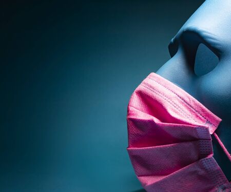 Medical pink mask put on a blue mask. black background.の写真素材