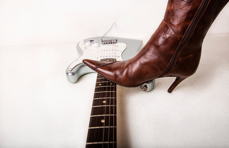 Silver electric guitar and brown womens high heels boots isolated on white background. High quality photoの写真素材