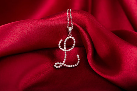 Silver necklace with a diamond pendant on red fabric backgroundの写真素材