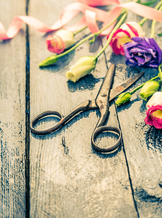 Flowers with scissors,  pink ribbon on old blue tableの写真素材