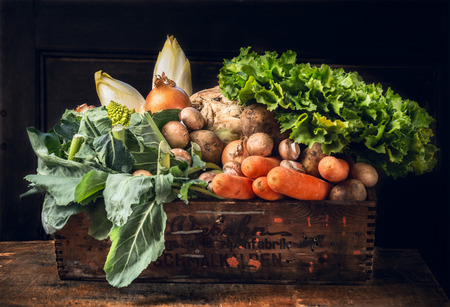 various of fresh vegetables in old box over dark wooden wallの写真素材