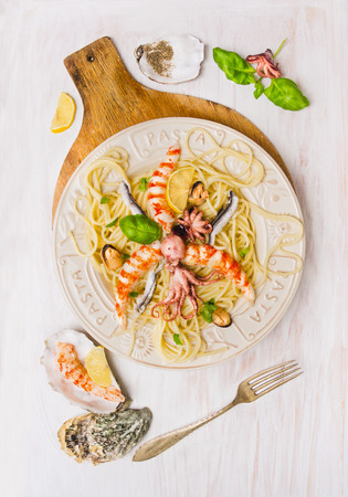 seafood spaghetti with mussel, anchovy, baby octopus and big shrimp, on white wooden background, top viewの写真素材