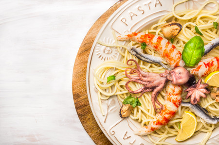 seafood spaghetti with whole baby octopus and big Shrimp in plate on white wooden background, close upの写真素材