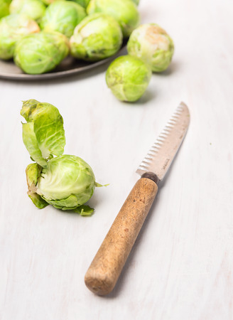 Fresh Brussels sprouts peeling with vintage knife on white wooden tableの写真素材