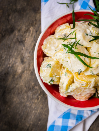 Potato salad bowl in red and blue napkin napkin on old wooden table, top viewの写真素材
