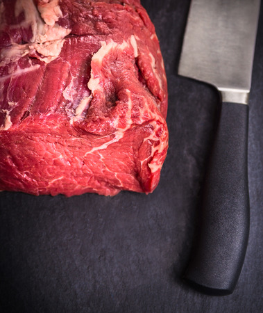 raw fillet of beef on slate table with knife, top viewの写真素材