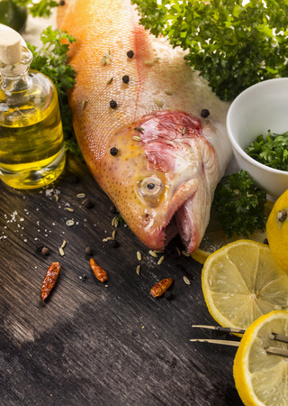 raw rainbow trout with spices and lemon on dark wooden table, preparationの写真素材