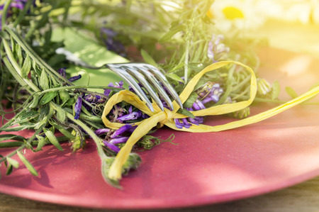 Summer table decoration with vetch flowers and fork on red plateの写真素材