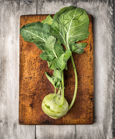 Fresh Kolrabi with leaves  on cutting board and white wooden table , top viewの写真素材