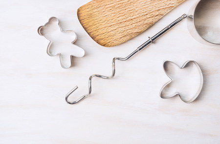 cookie cutters and wooden spoon on white wooden background