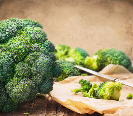 broccoli head on table in crumpled paper with knife on wooden backgroundの写真素材